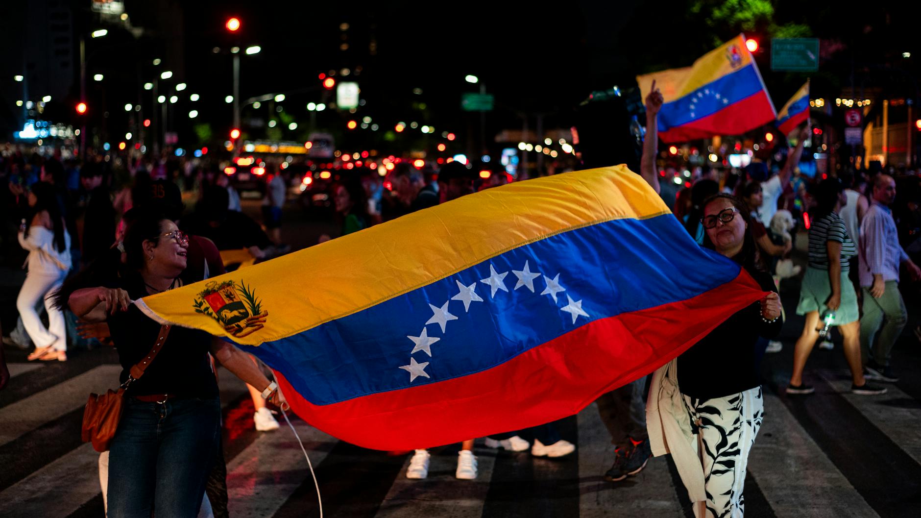Wenezuelczycy z flagami świętują nocą na ulicy w Buenos Aires