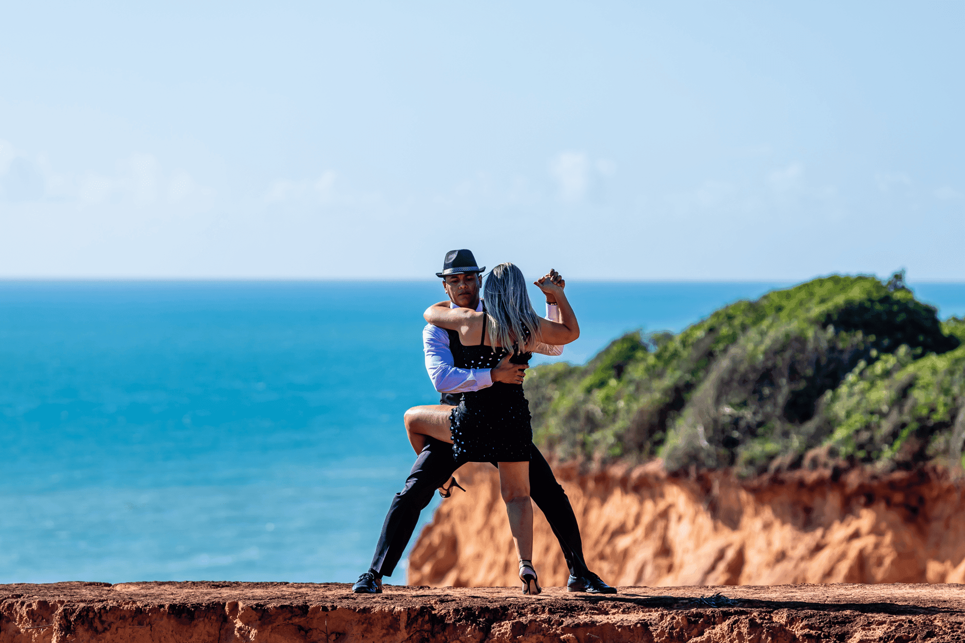 Jak budować taneczne znajomości w podróży, nie znając dobrze języka Para tańcząca tango na klifie nad oceanem w Brazylii