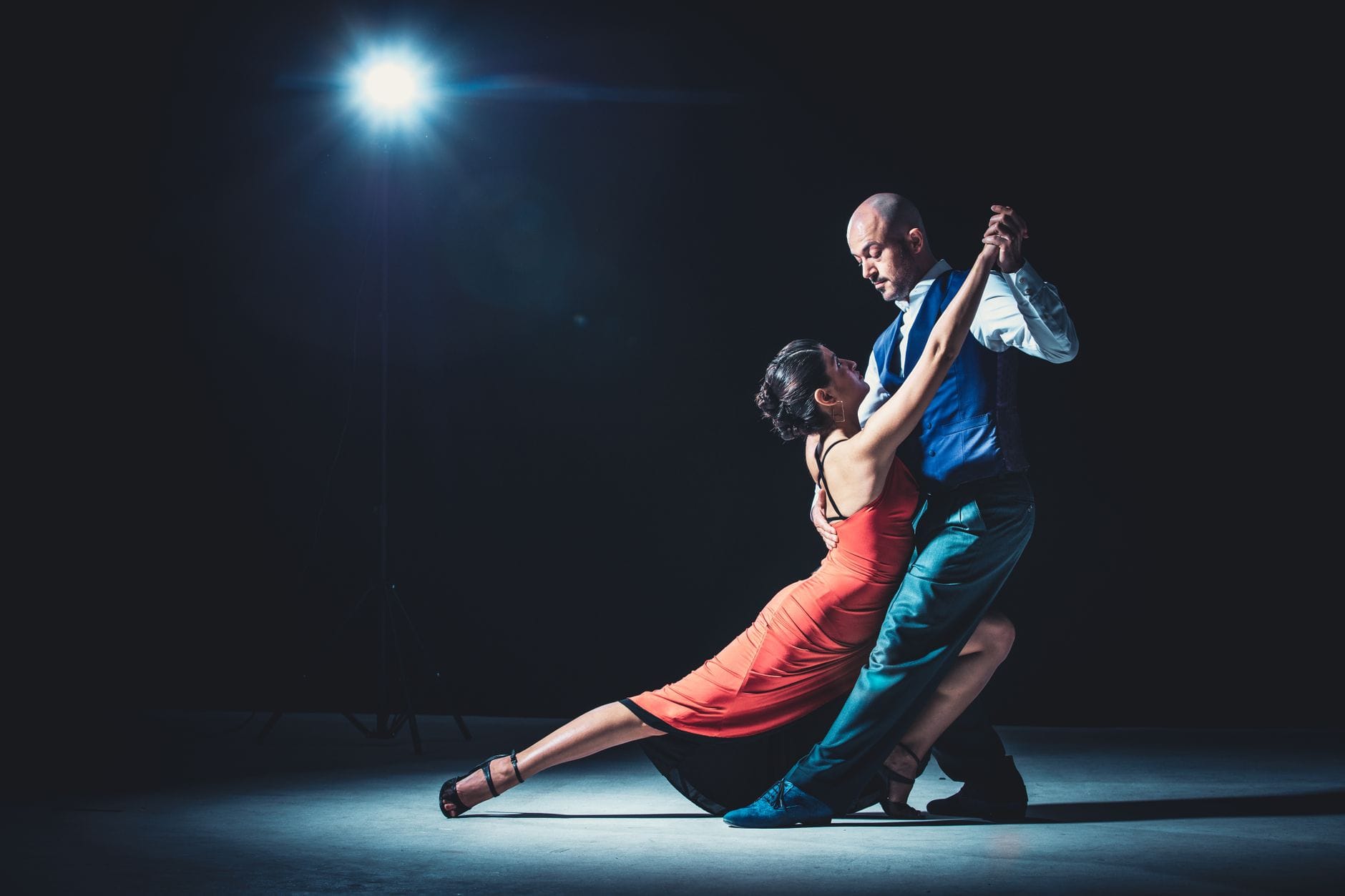 Elegancka para tańczy namiętny tango pod mocnym światłem reflektorów