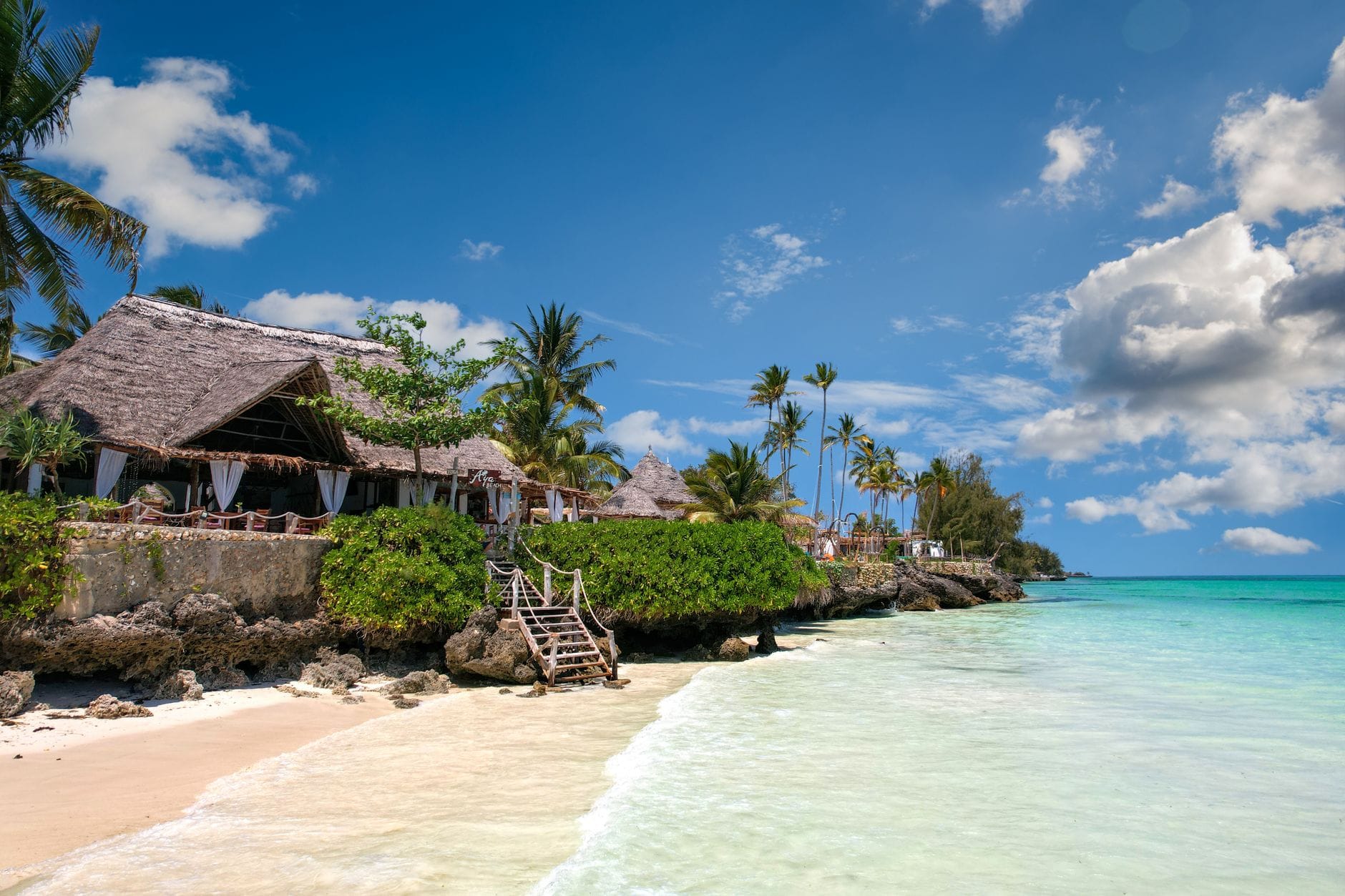 Plaża na Zanzibarze z palmami, turkusowym morzem i willą przy brzegu